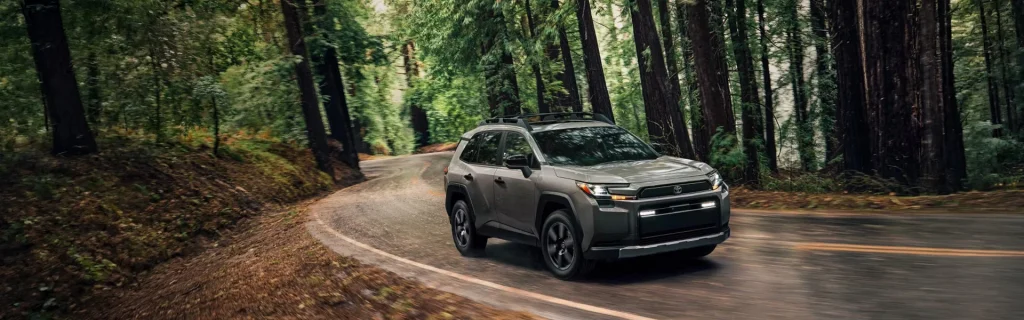 A Toyota RAV4 driving along a winding road through a forest.